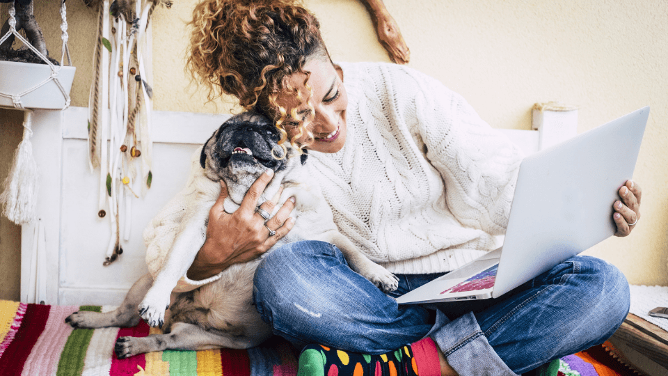 woman hugging pug while holding laptop